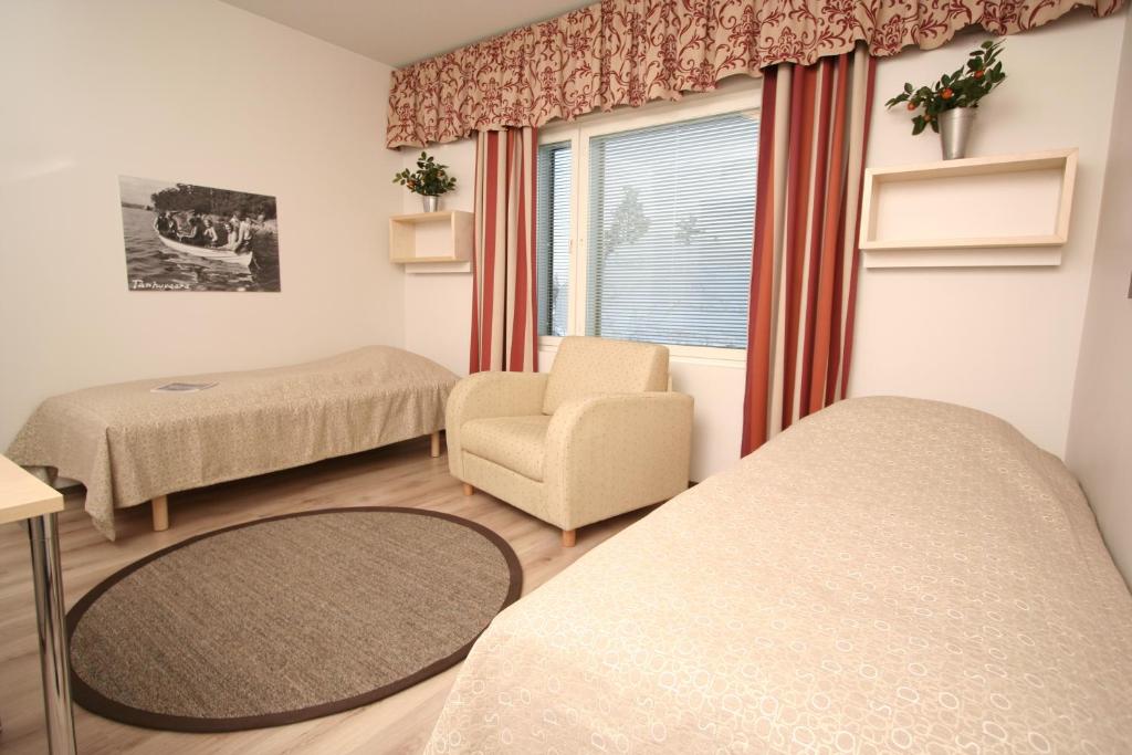 um quarto com duas camas e uma cadeira e uma janela em Tanhuvaara Sport Resort em Savonlinna
