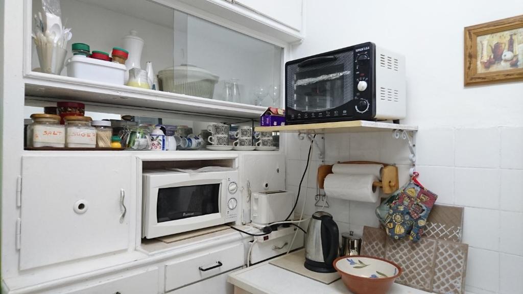 een kleine keuken met een magnetron en een aanrecht bij Stella Maris Hosting in Haifa