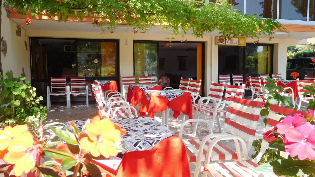 ベッラーリア・イジェア・マリーナにあるHotel Le Pleiadiの赤白の椅子と花のテーブル