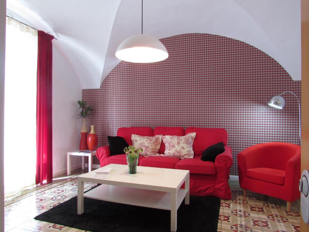 a living room with a red couch and a table at Apartamentos La Machacona Plaza de Santiago in Cáceres