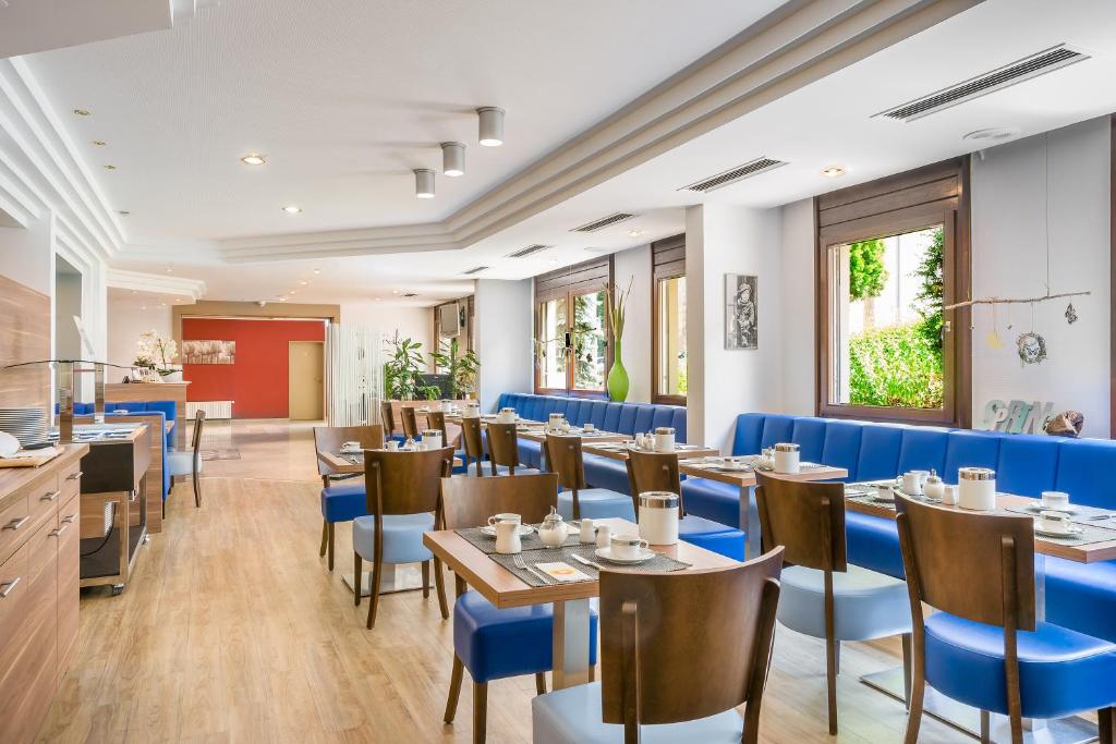 a restaurant with tables and blue chairs at Hotel Rega Stuttgart in Stuttgart