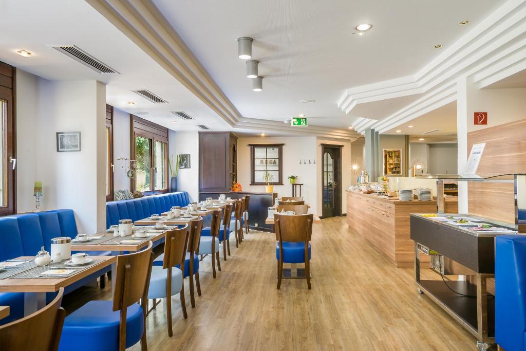 a dining room with tables and blue chairs at Hotel Rega Stuttgart in Stuttgart