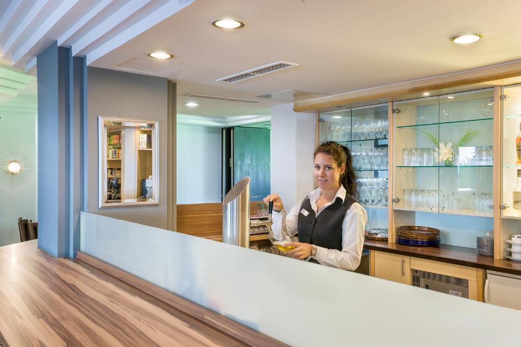 a woman standing behind a counter in a kitchen at Hotel Rega Stuttgart in Stuttgart