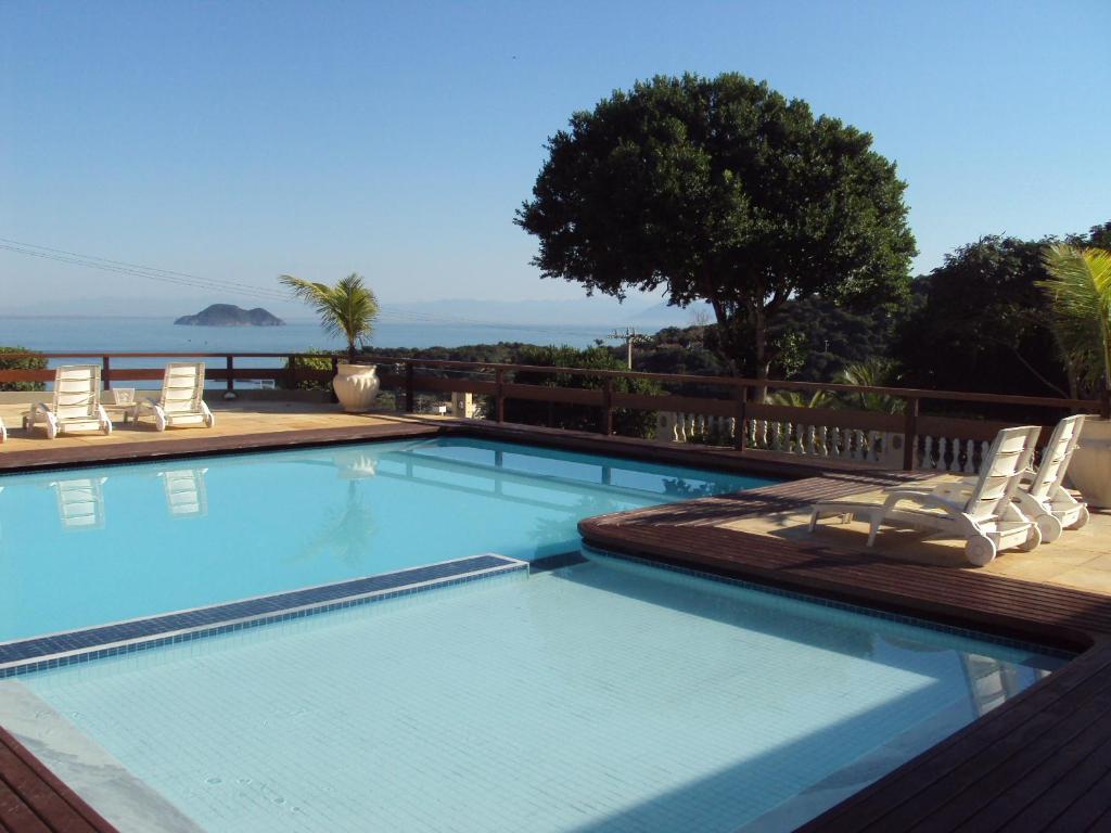 een zwembad met ligstoelen en de oceaan bij Barlavento Suites in Búzios