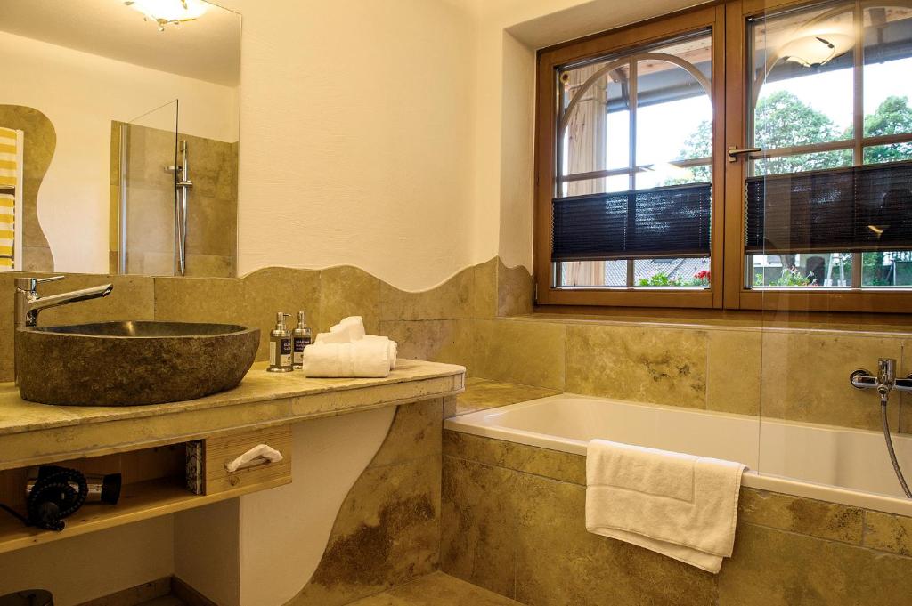 e bagno con vasca, lavandino e vasca. di Der Paternwirt a Maria Luggau