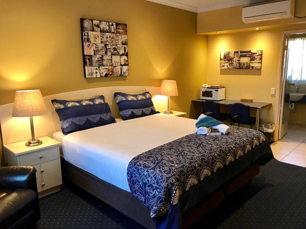 Kyabram Motor Inn في Kyabram: غرفة فندقية بسرير كبير وكرسي