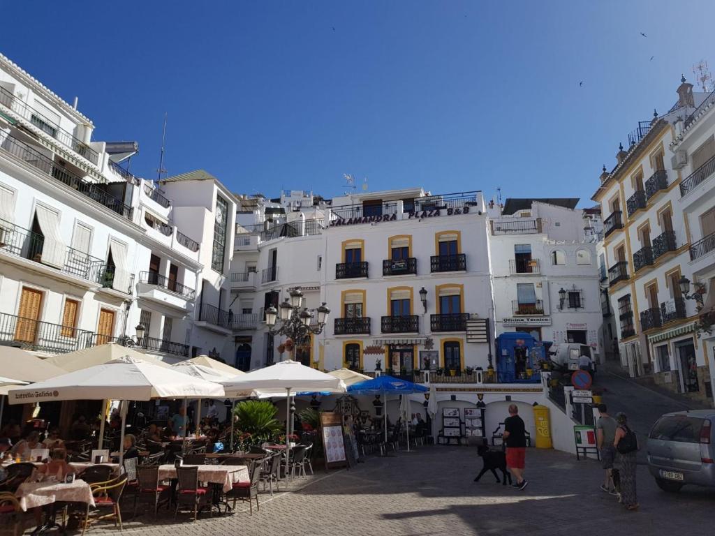 una calle con mesas y sombrillas frente a los edificios en Salamandra Plaza, en Cómpeta