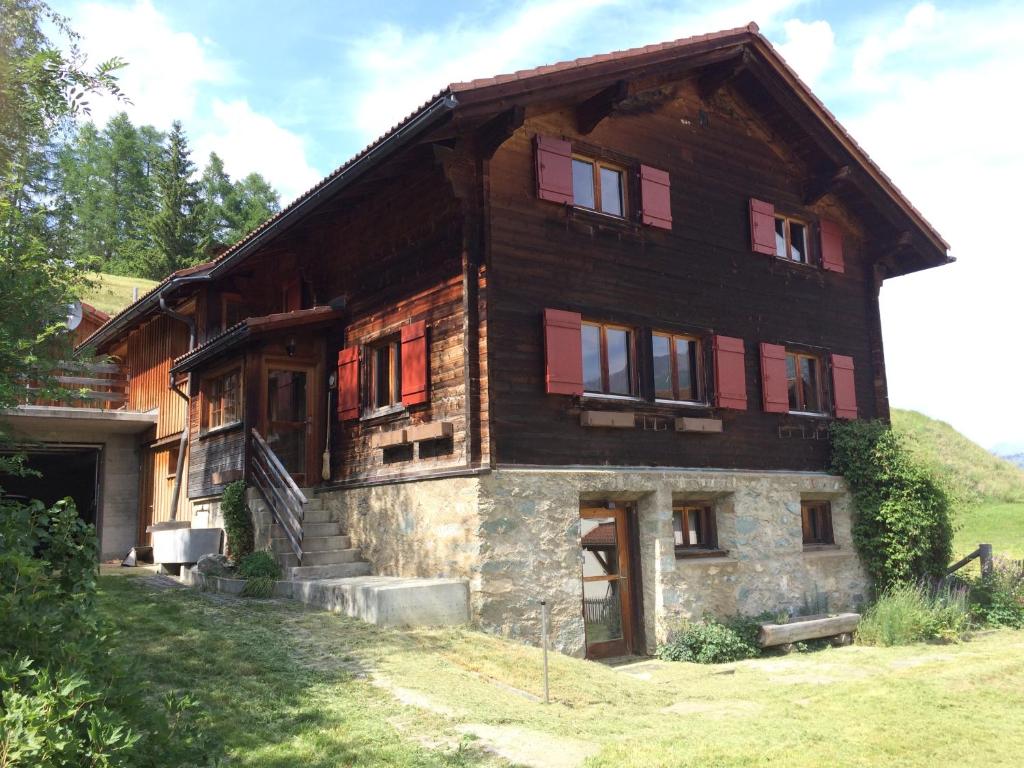 een groot houten huis met rode luiken bij Chalet Nidus Montis in Wergenstein