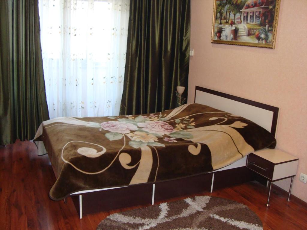 a bedroom with a bed with a blanket with flowers on it at Apartment Lux on Univermag Ukraina Center, 76 in Zaporozhye