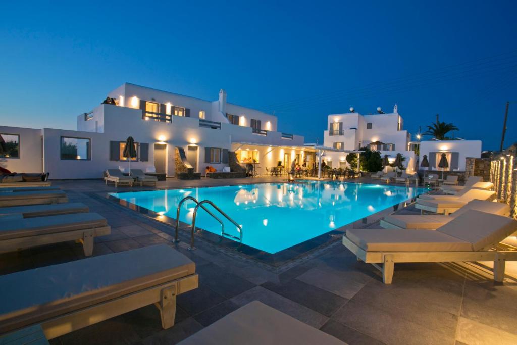 ein Pool mit Stühlen und Gebäuden in der Nacht in der Unterkunft Anna-Maria Mykonos Hotel in Glastros