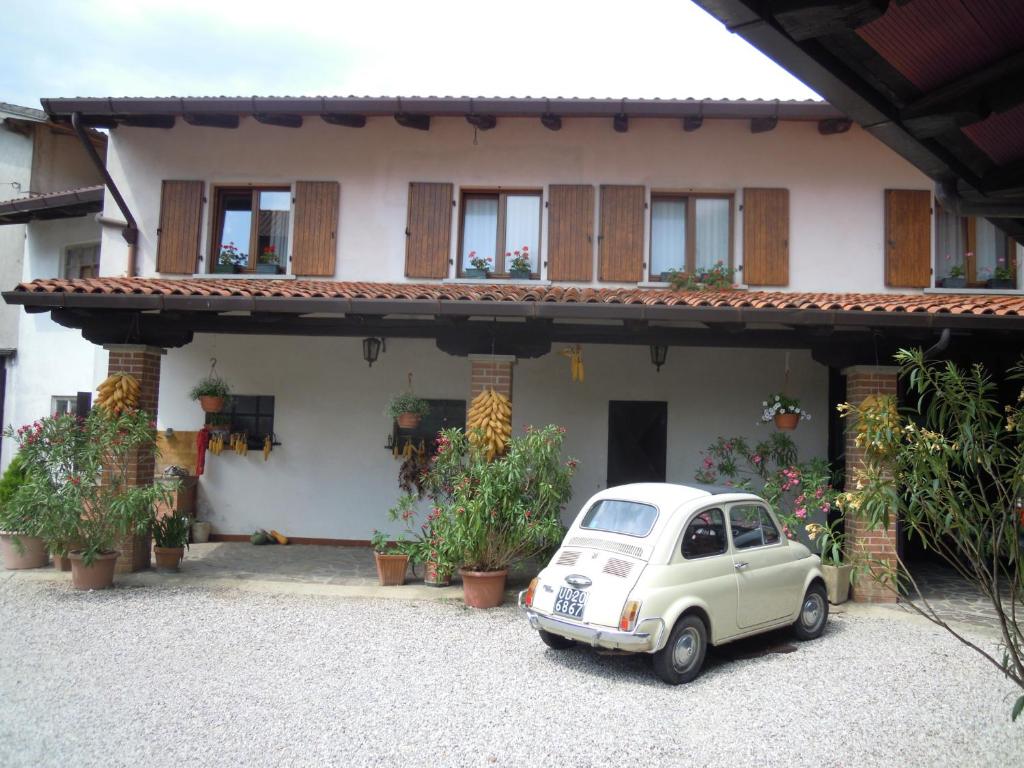 a small white car parked in front of a house at B&B Emma in Torreano
