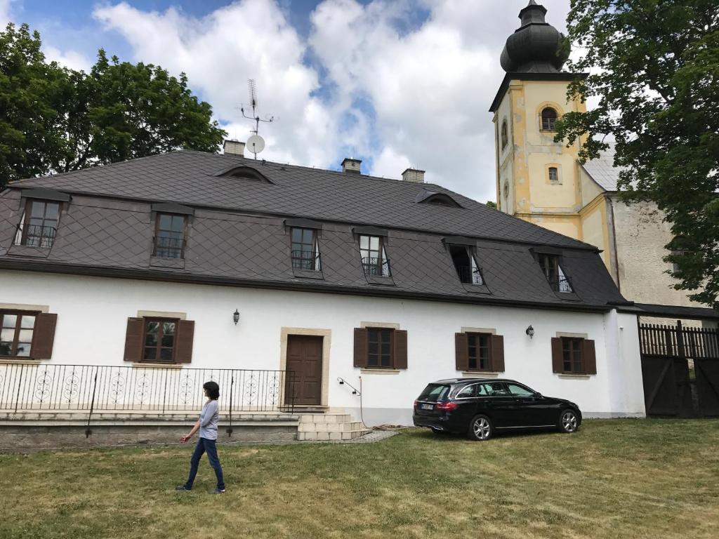 a person walking in front of a large white building at Sancta Katharina in Rozvadov