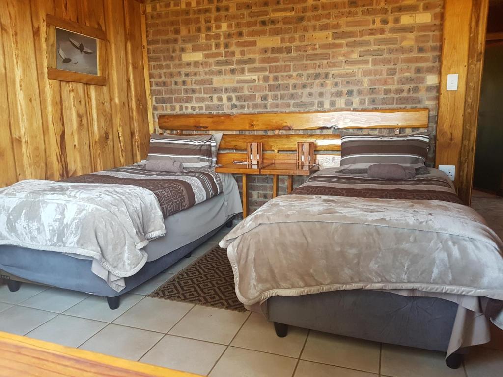 two beds in a room with a brick wall at Rainbow Lodge in Belfast