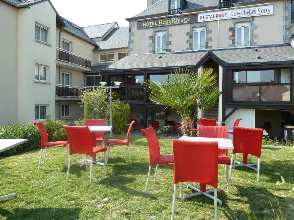 a group of red chairs and tables in front of a building at Hotel Beau Rivage in Le Vivier-sur-Mer