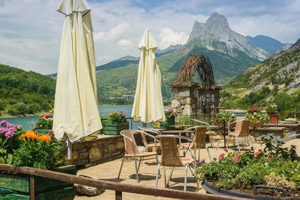 un patio con sillas y sombrillas frente a una montaña en Hotel La Casueña, en Lanuza