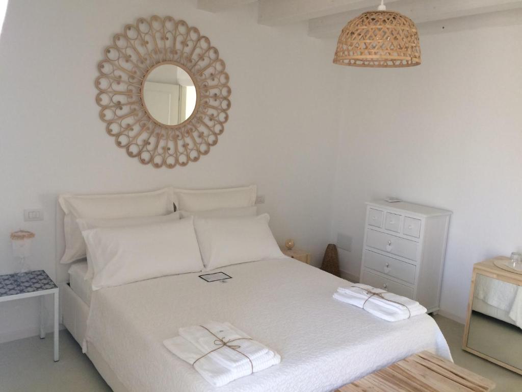 a bedroom with a white bed and a mirror at Casa Memi in Marzamemi