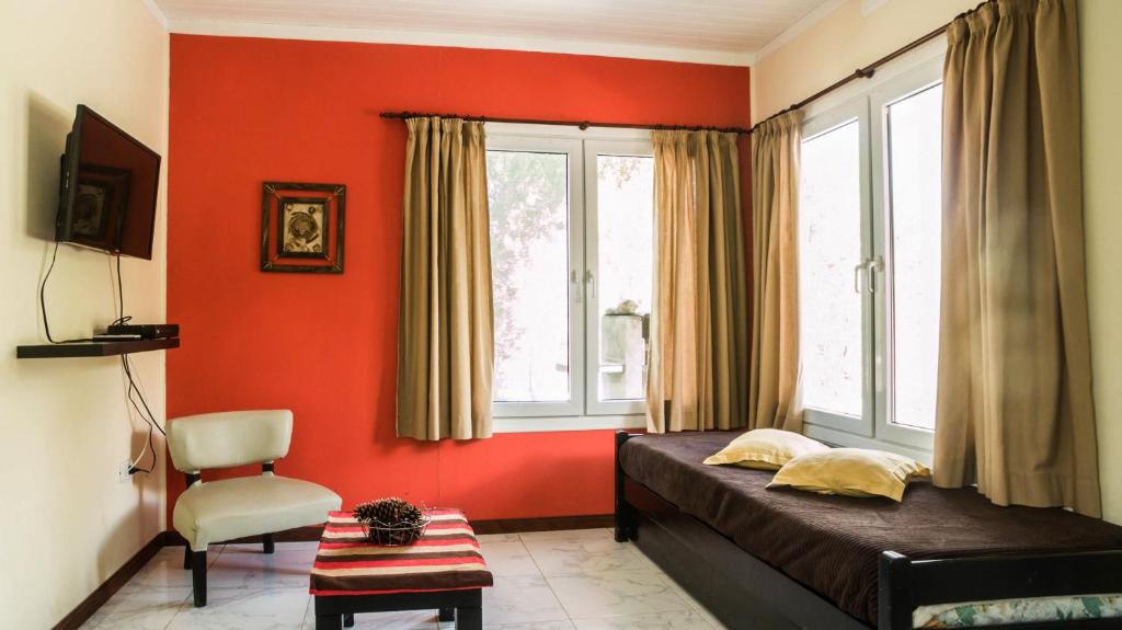 1 dormitorio con paredes de color naranja, 1 cama y 1 silla en Estancia Río Abajo en Trevelín