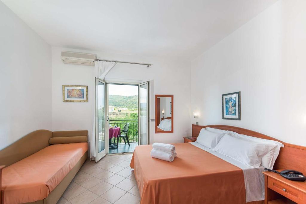 een slaapkamer met een bed, een bank en een balkon bij Albergo Villa A Mare in Peschici