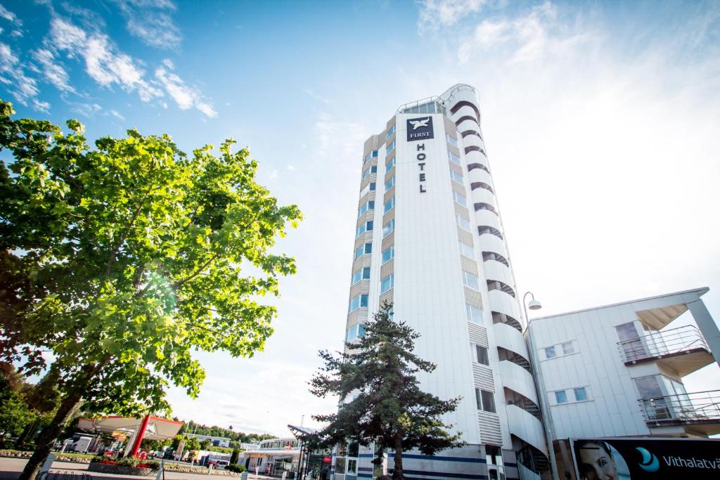 Un alto edificio bianco con un albero davanti di First Hotel Jönköping a Jönköping