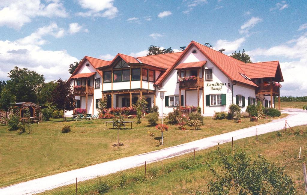 a large house with a red roof on a road at Landhaus Dampf in Bad Blumau