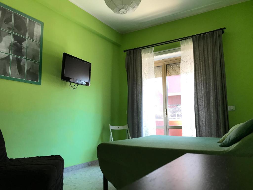 una camera da letto con pareti verdi, un letto e una TV di Arches Inn a Roma