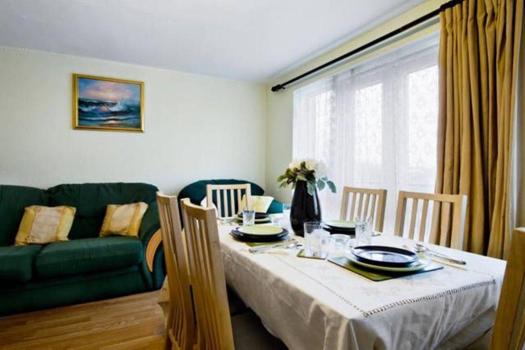 a dining room with a table and a green couch at Wood Green direct tube Eurostar Heathrow, close Ally Pally in London