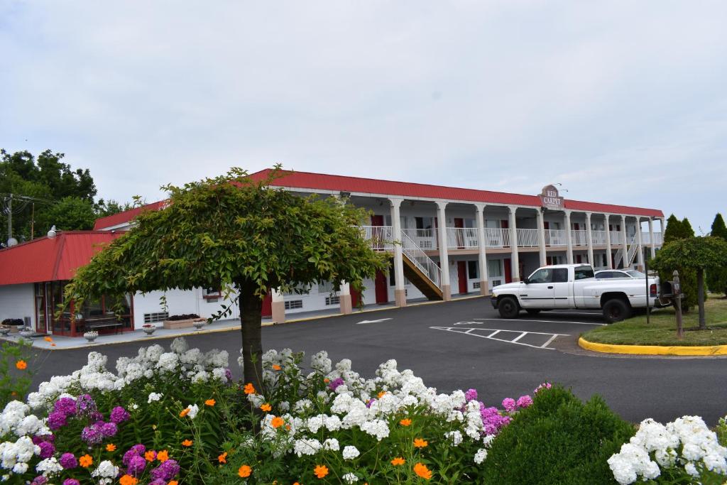 a white truck parked in front of a building with flowers at Red Carpet Inn & Suites Culpeper in Culpeper