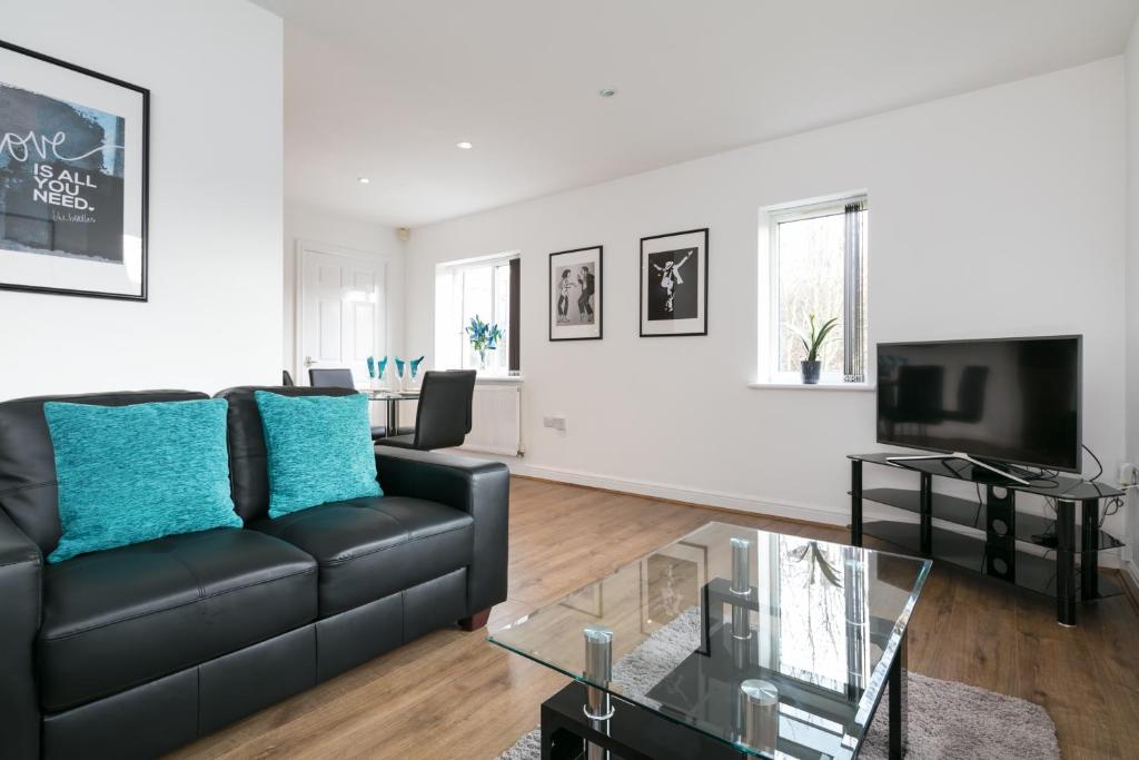 a living room with a black couch and a tv at Bluestone Apartments - Didsbury in Manchester
