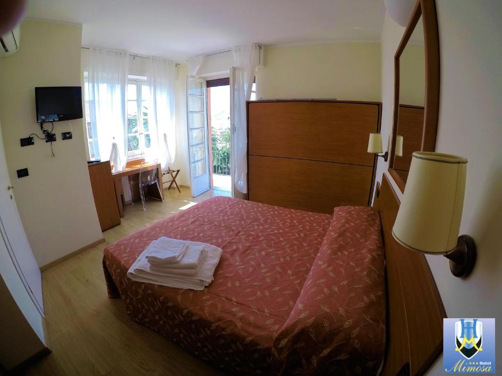 1 dormitorio con cama, lámpara y escritorio en Hotel Mimosa, en Spotorno