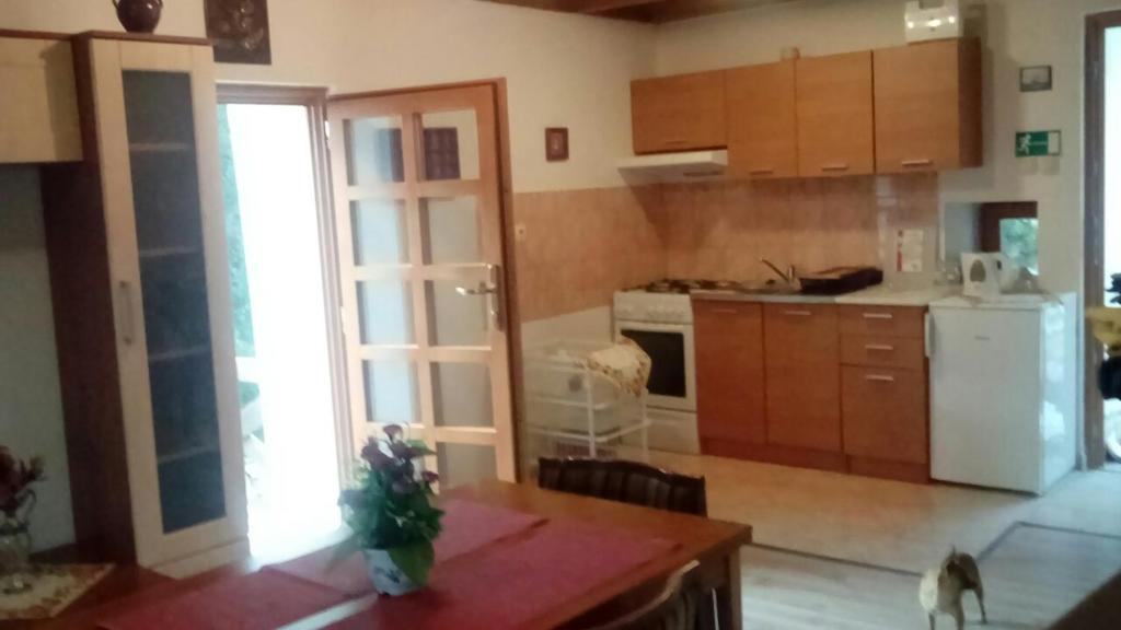 uma cozinha com armários de madeira e um frigorífico branco em Apartments Orlí Hnízdo em Rab