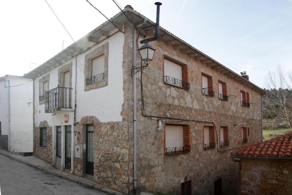 un antiguo edificio de piedra con ventanas y una calle en Casa Rural El Fronton, en Vadillo