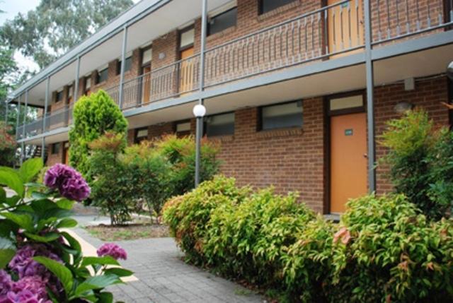 ein Backsteingebäude mit einem Balkon an der Seite in der Unterkunft Red Cedars Motel in Canberra