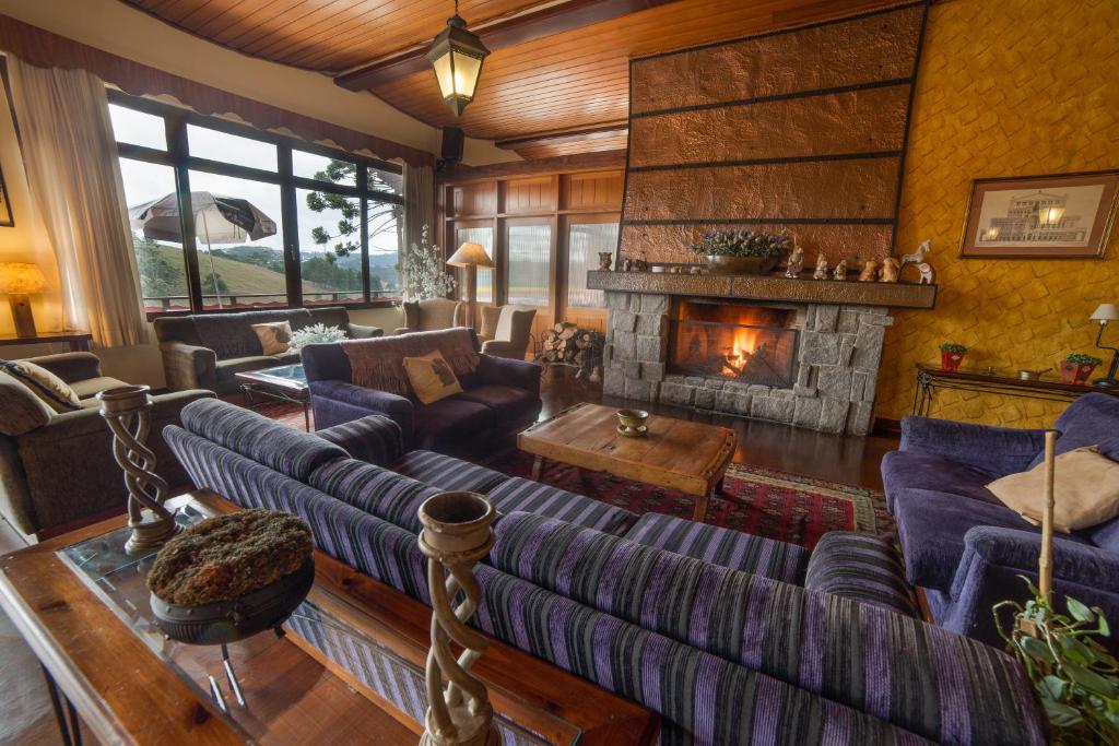 a living room with couches and a fireplace at Hotel Recanto São Cristóvão - Próximo ao parque Tarundu in Campos do Jordão