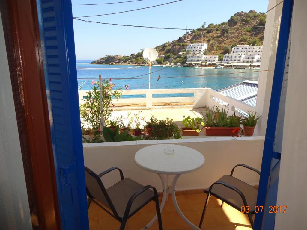 
a dining room table with a balcony overlooking the ocean at Scirocco Rooms in Loutro
