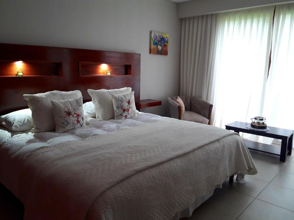 una habitación con una cama grande con sábanas y almohadas blancas en Aires del Norte, en Federación