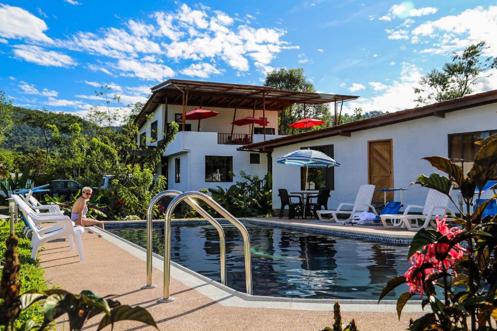 a woman sitting on a chair next to a swimming pool at Coffee Lodge Cristal Glamping & Spa in Mindo