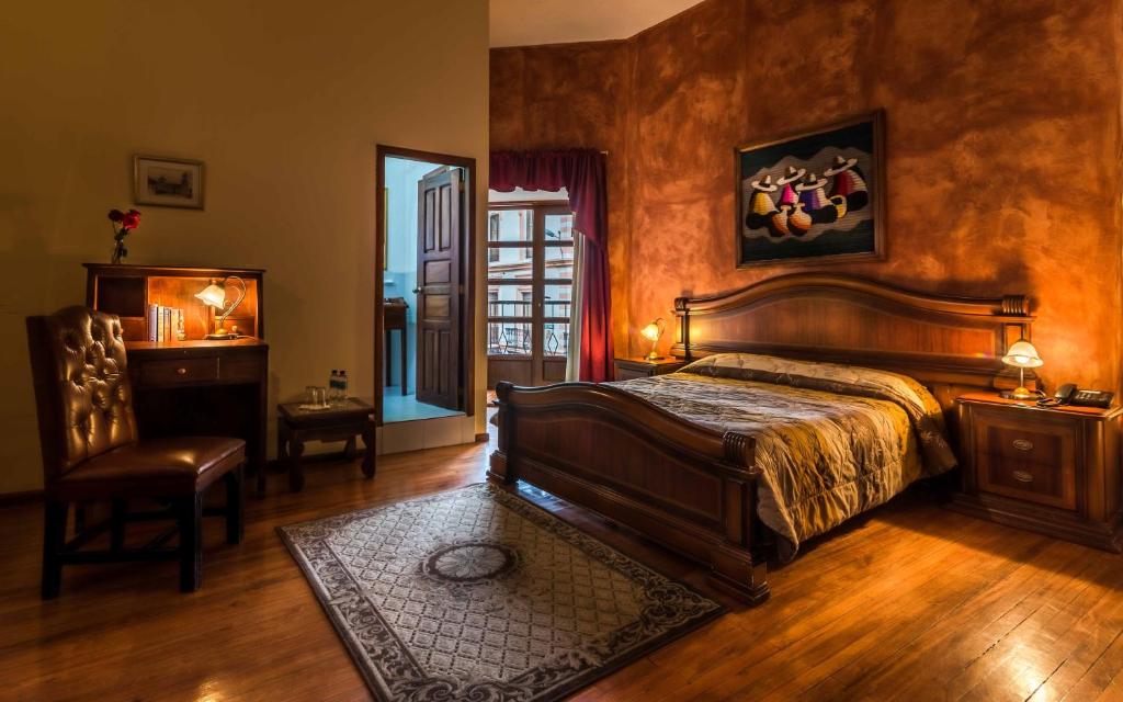 a bedroom with a bed and a table and a chair at Hotel San Francisco De Quito in Quito