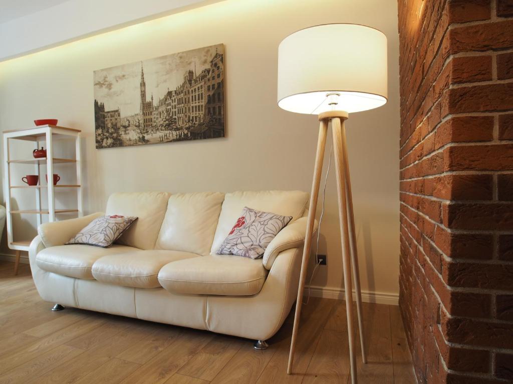 een woonkamer met een witte bank en een vloerlamp bij Grand Tourist Simple Rest Apartments in Gdańsk