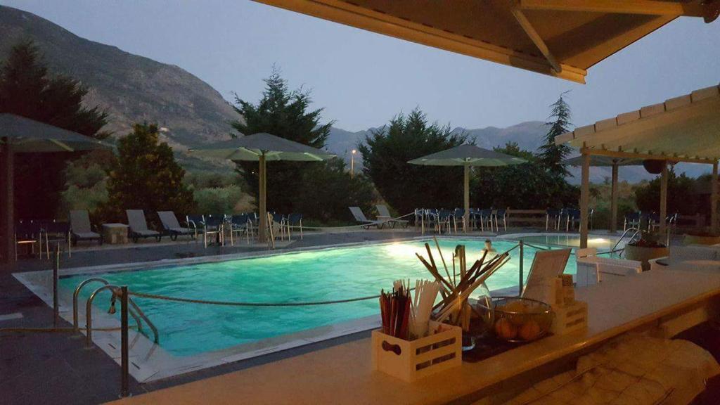 una grande piscina con sedie e ombrelloni di Hotel Iliana a Mandrotopos