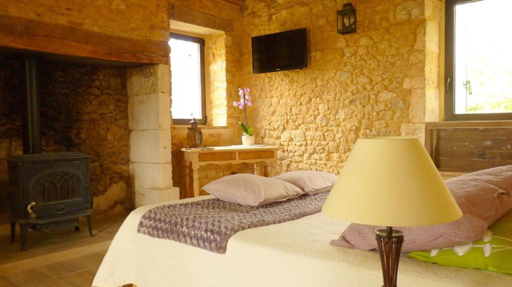 a bedroom with a bed and a wood stove at Aux fontaines d'Eyvigues in Eyvignes-et-Eybènes