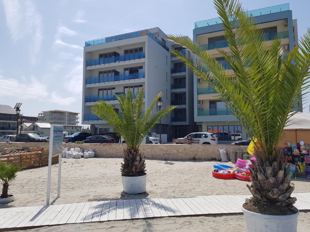 two palm trees on the beach in front of a building at WAVE 1 Promenada Apartments in Mamaia Sat/Năvodari