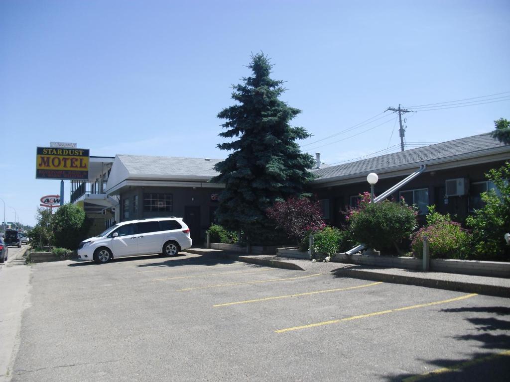 a white car parked in a parking lot in front of a motel at Stardust Motel in Camrose