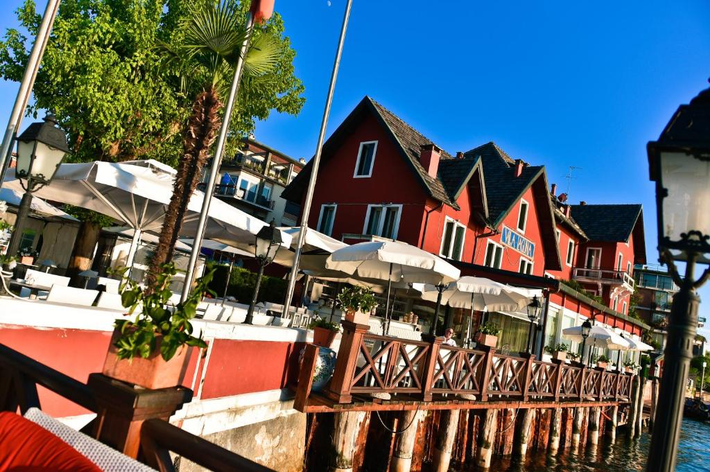 a red building with tables and umbrellas next to the water at Hotel Villa Laguna in Venice-Lido