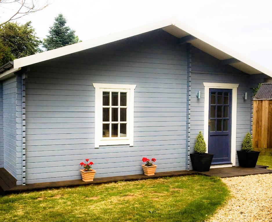 Una casa azul con dos macetas de flores. en Walnut Tree Lodge en Aylsham