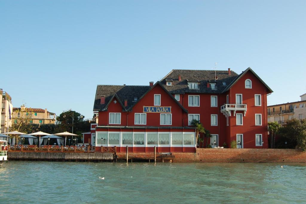 a large red building next to a body of water at Hotel Villa Laguna in Venice-Lido