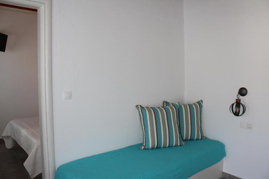 a bed with two pillows on a white wall at Studios Betty in Plaka Milou