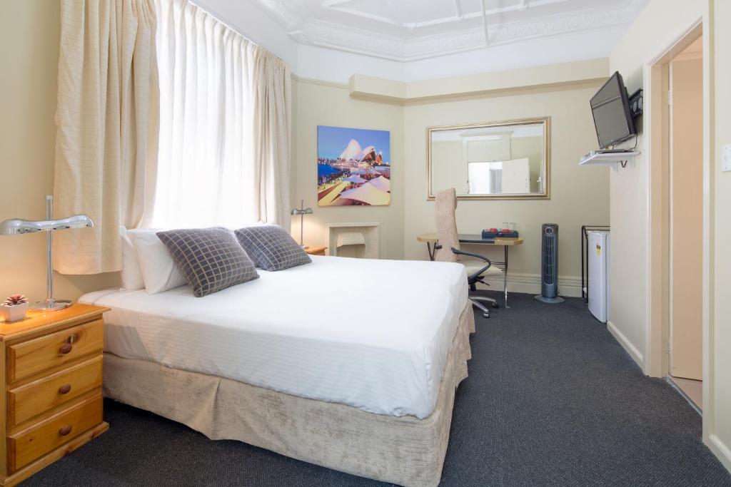 een slaapkamer met een bed, een bureau en een raam bij Neutral Bay Lodge in Sydney