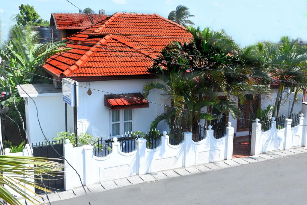 a white fence in front of a white house at Bon Voyaage Tourist Inn in Trincomalee