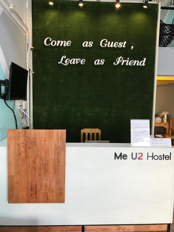 una pizarra verde con un cartel en la parte superior de una mesa en U2 & i-smile Hostel, en Chiang Mai