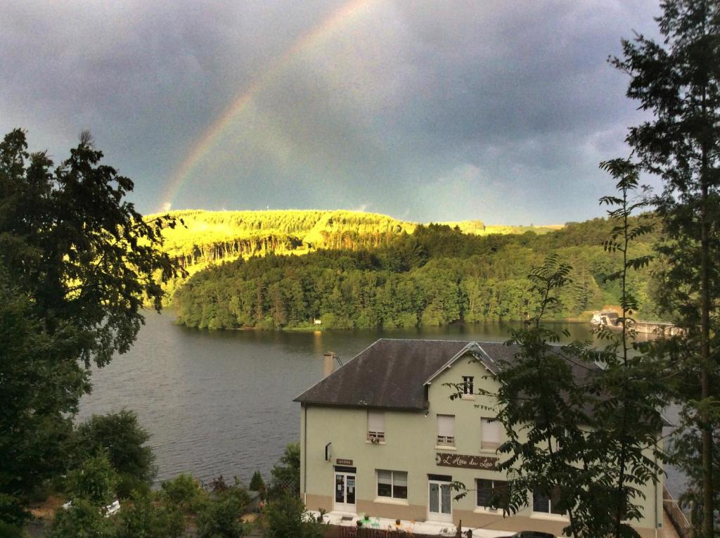 Treignac的住宿－Hôtel du Lac，一座有房子和建筑的湖上空的彩虹